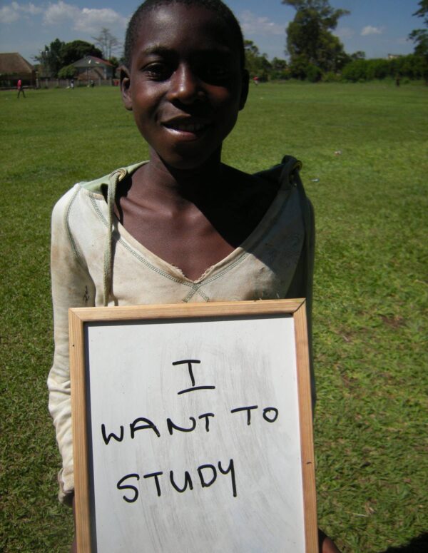 Learning child holds up a sign saying 'I want to study'