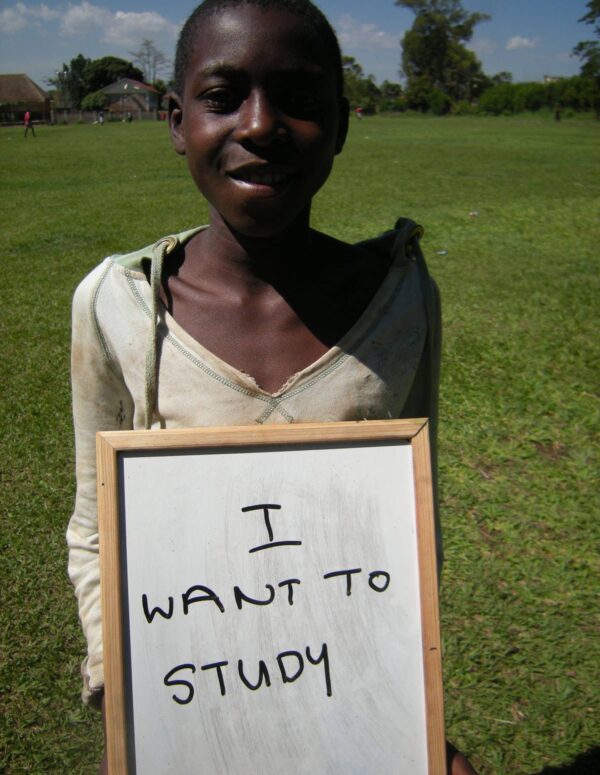 child holds up a sign saying 'I want to study'