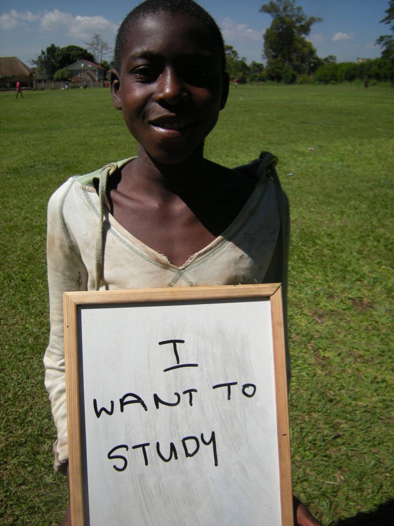 child holds up a sign saying 'I want to study'