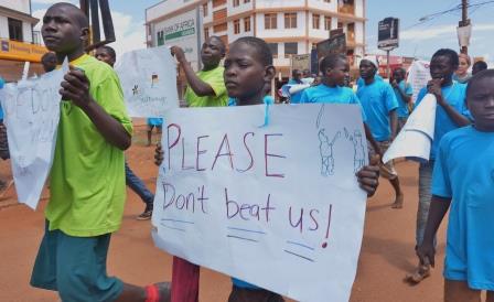 a child holding a sign saying 'please don't beat us'