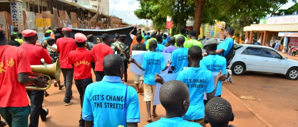 children walking in a protest with tops saying 'let's change the streets' written on the back