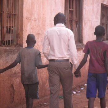 a worker walks on the street with 2 children