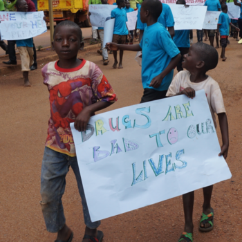 Boys carrying a sign reading 'Drugs are bad to our lives'.