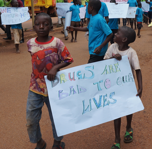 Boys carrying a sign reading 'Drugs are bad to our lives'.