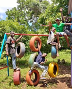 Children playing on a frame with tyres hanging from it