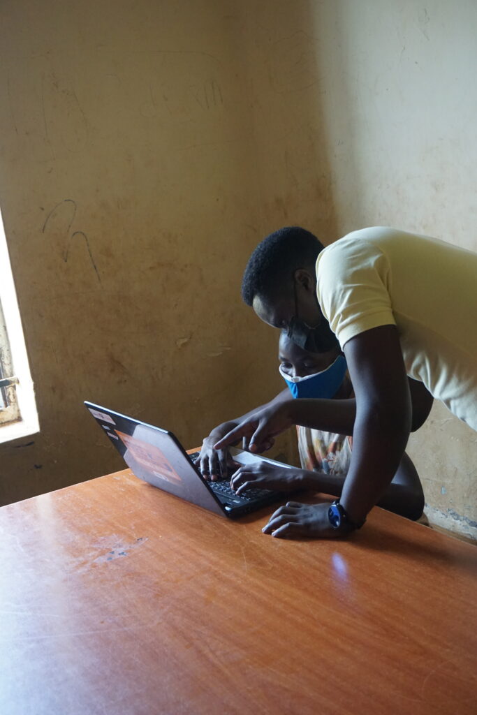 A teacher helping a child use a laptop
