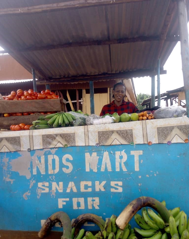 Patience pictured behind a stall selling fruit and vegetables