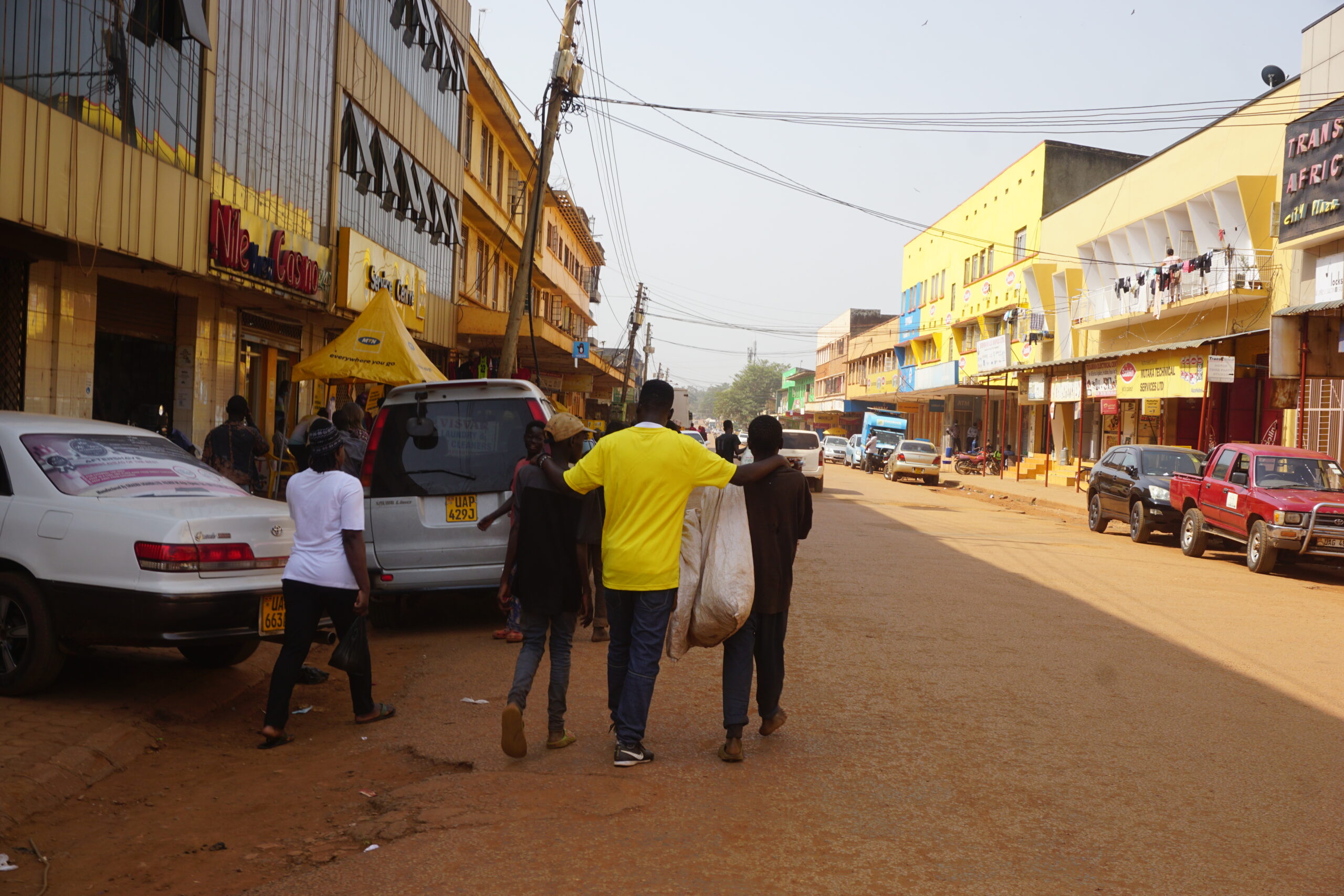 A man wearing S.A.L.V.E's yellow tshirt walks down a street with a group of boys
