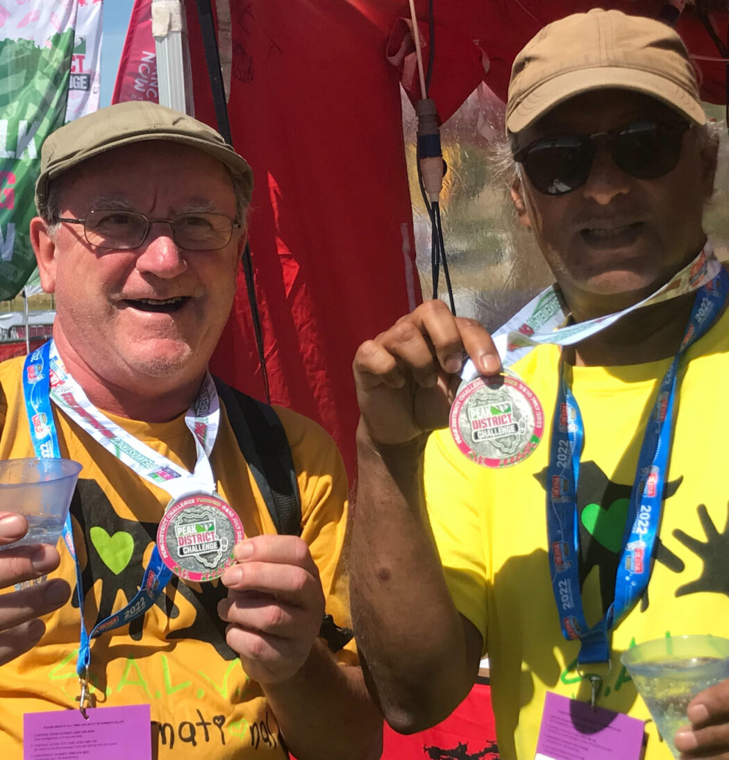 Steve and Taresh holding up their Peak District Challenge medals