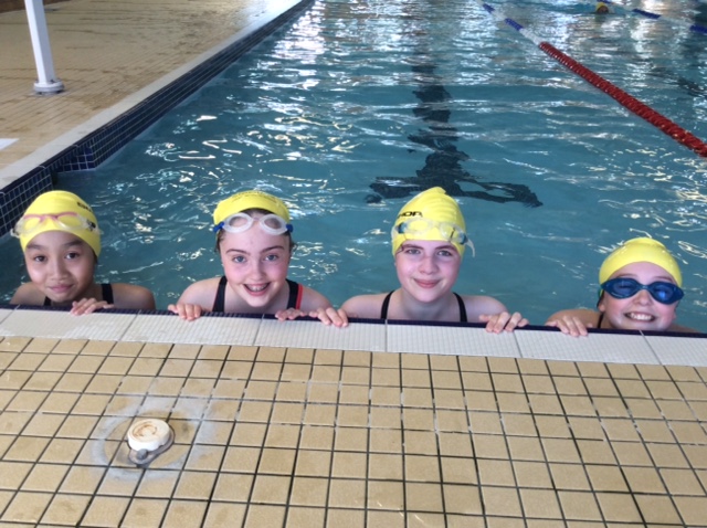 children in the swimming pool wearing SALVE swimming caps