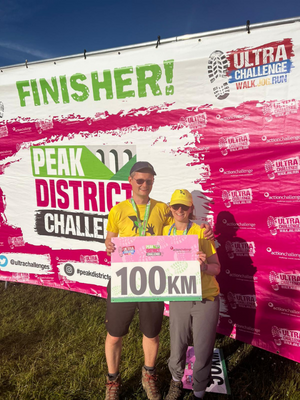 Hannah and Jonnie at the finish line holding the 100km sign