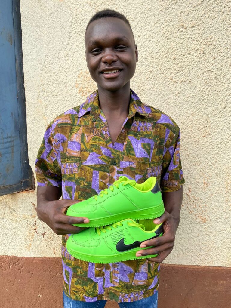 Young person smiling, holding a pair of trainers