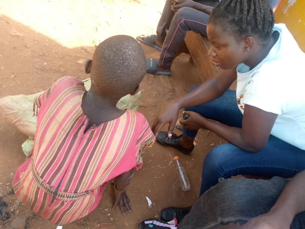 A child on the streets, kneeling down being talked to by a S.A.L.V.E. International social worker who is looking sympathetic