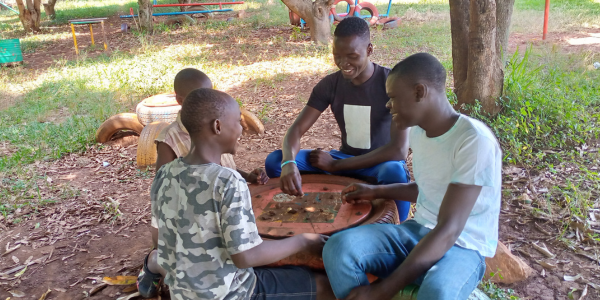 Four teenage boys, sitting round a table and playing a board game, smiling