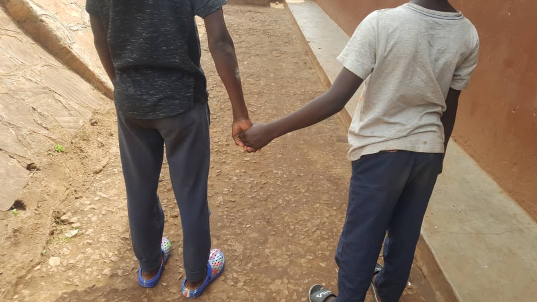 A downward angle shot of a child, hand in hand with an adult in a street setting