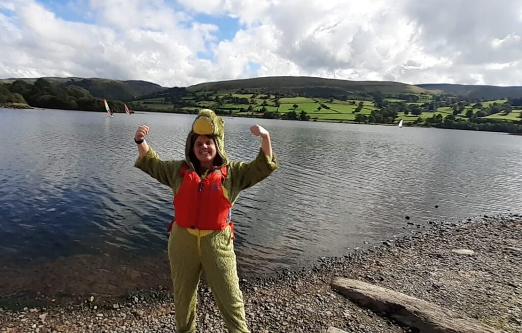 Nicola cheering in front of Bala Lake, wearing a crocodile onesie