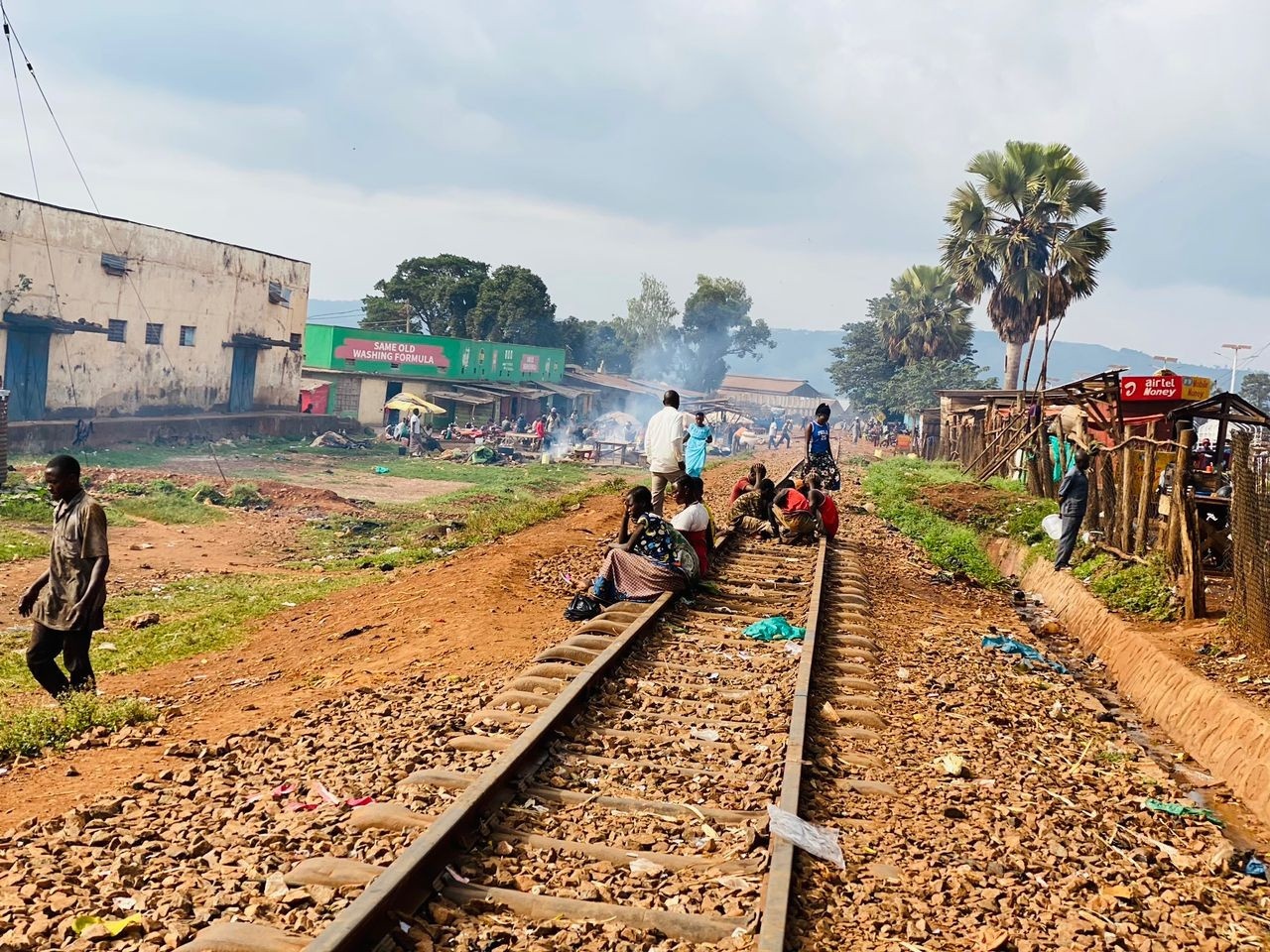 Street connected children sitting on a railway track in Uganda in a suburban scene. There is rubbish on the floor.