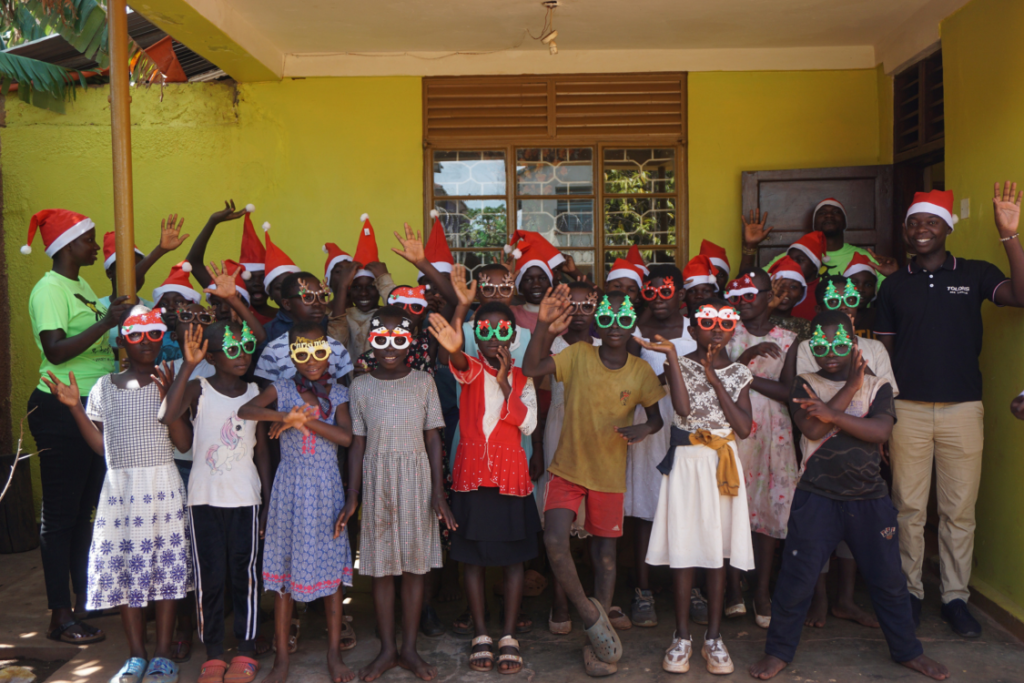 A group of children smiling wearing Christmas hats and glasses