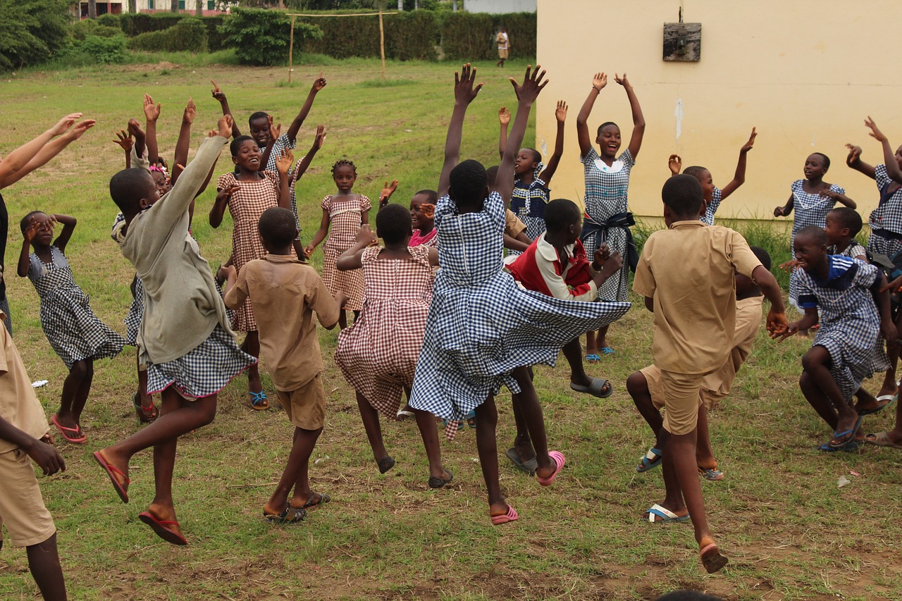 A group of school children jumping up together outside. It is a happy picture.