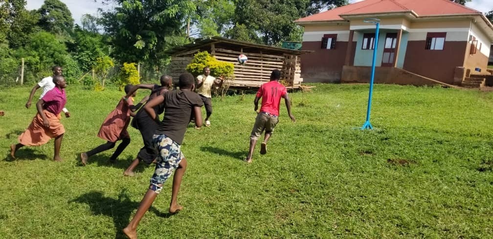 A group of children at the SALVE residential site are playing football. This is an action shot of the children running to chase the ball.