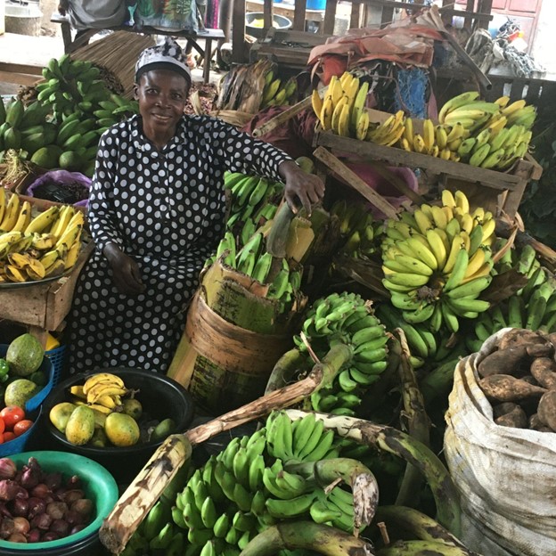 A woman smiling while at a stall selling fruit