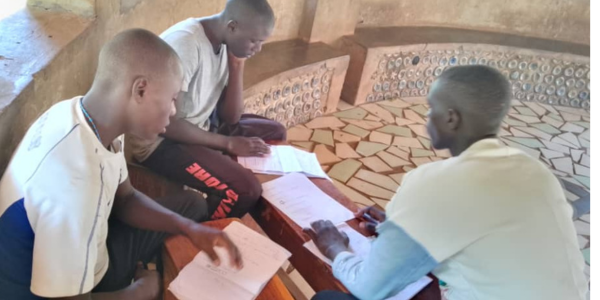 3 young men looking at written work, studying