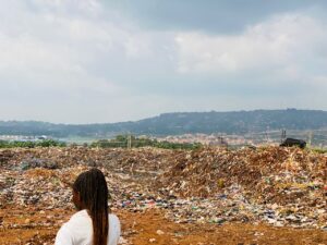 A woman is pictured against the backdrop of a rubbish dump in Jinja, Eastern Uganda