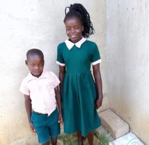 Two children, smiling at the camera wearing school uniform
